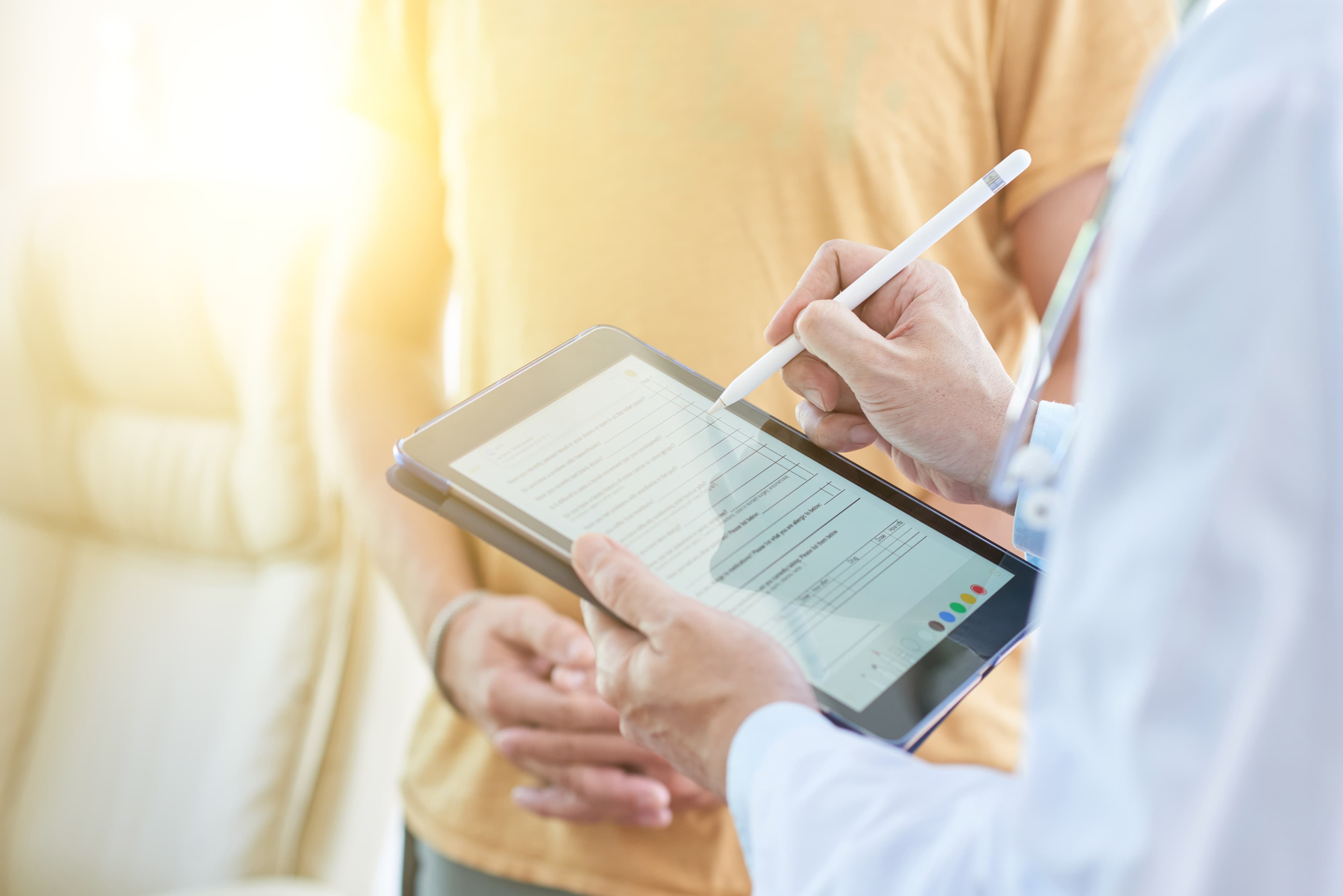 Clinician using a stylus on a tablet to review a patient document with the patient alongside